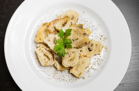 top of view of dish of italian swivels pasta with porcini mushrooms and sauce bechamel with pepper on old black tableの写真素材