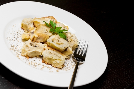 close-up of dish of italian swivels pasta with porcini mushrooms and sauce bechamel with pepper near fork on black tableの写真素材