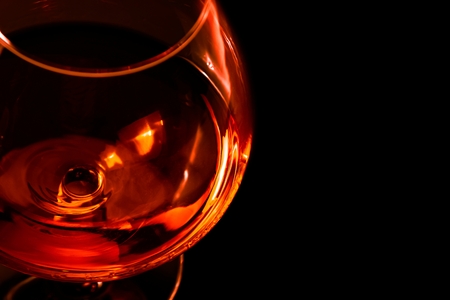 top of view of snifter of brandy in elegant typical cognac glass on black background with red and orange reflectionの写真素材