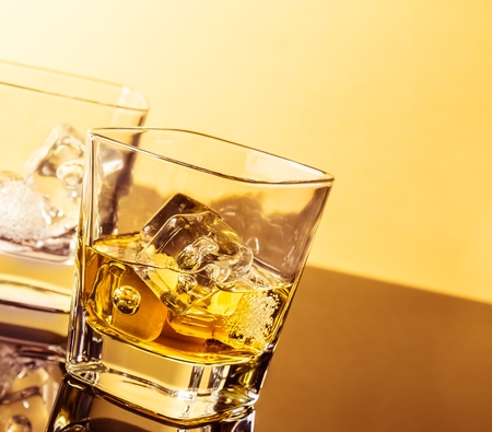 two glasses of whiskey on table with reflection, warm atmosphere, time of relax with whiskyの写真素材