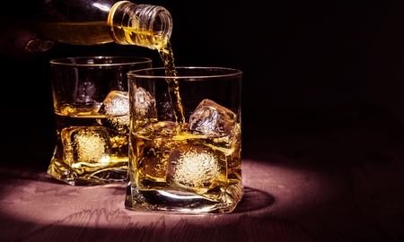barman pouring whiskey in the glasses on wood table, warm atmosphere, old style, time of relax with whisky with space for textの写真素材