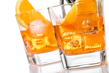 detail of two glasses of spritz aperitif aperol cocktail with orange slices and ice cubes on white backgroundの写真素材