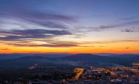 sunset scene with mountains in background, colorful sky with soft clouds and city Matera in foreground, industrial viewの写真素材