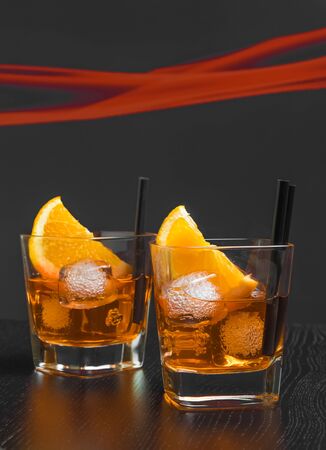 two glasses of spritz aperitif aperol cocktail with orange slices and ice cubes on wood tableの写真素材