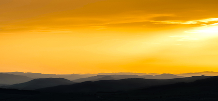 mountains silhouette at sunset, natural light tint warmの写真素材