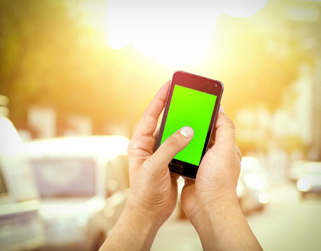 hand  of man use mobile smart phone with chroma key green screen on street outdoor background, new technology conceptの写真素材