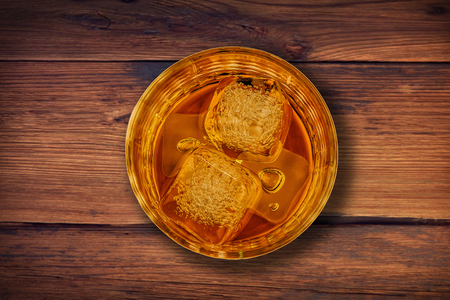 top of view of whiskey in glass with ice cubes on wood table background, whisky relax timeの写真素材