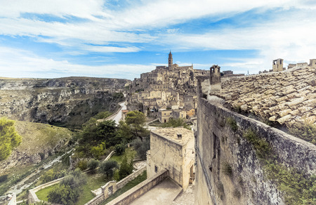 panoramic view of typical stones (Sassi di Matera) and church of Matera under blue sky, artistic...