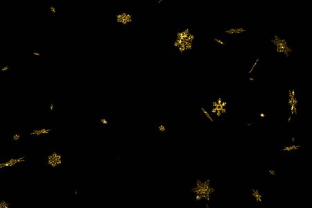 abstract gold glitter sparkle christmas snowflakes falling down snow from top, winter holiday xmas seamless loop on black backgroundの写真素材