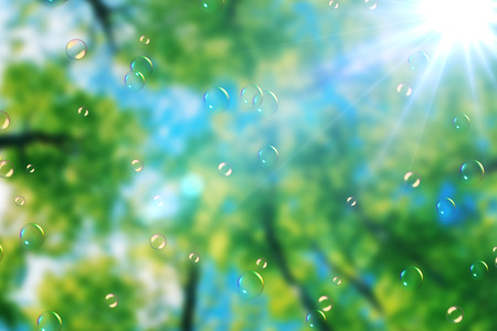 soap bubbles floating on green nature background under blue sky with sun rays light, bubble blower movementの写真素材
