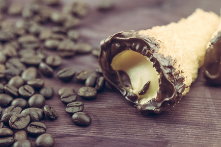 delicious sicilian cannolo cannellino sweet with pastry hazelnut chocolate and pastry cream near coffee beans, italian puff-pastry on wood background, nutrition and diet conceptの写真素材