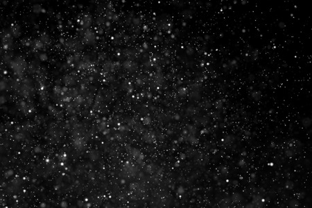 abstract dust particles flowing on dark background with light spotの写真素材