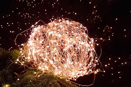abstract Christmas glitter lights ball on xmas tree with warm sparkle bokeh on black background,...