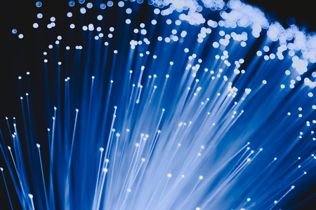 detail of blue growing bunch of optical fibers background, fast light signal for high speed internet connectionの写真素材