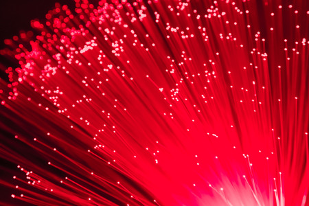 detail of red growing bunch of optical fibers background, fast light signal for high speed internet connection conceptの写真素材