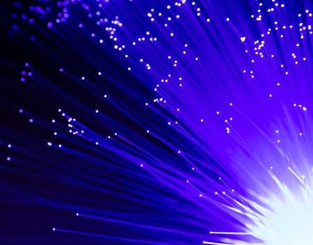 Detail of blue growing bunch of optical fibers background, fast light signal for high speed internet connectionの写真素材
