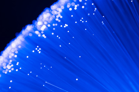 detail of blue growing bunch of optical fibers background, fast light signal for high speed internet connectionの写真素材