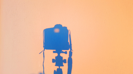 silhouette of camera reflex on the wall at sunset, concept of technology photography equipmentの写真素材