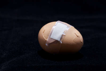 Broken egg with sticking plasterの写真素材