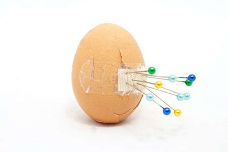 Broken egg with sticking plaster pin の写真素材