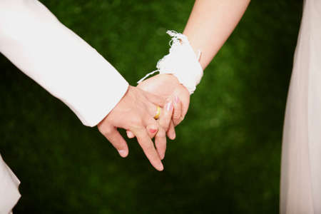 Closeup of a bride and groom holding hands isolated の写真素材