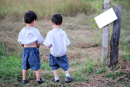 Children relieving themselves at the side of a fieldのeditorial素材