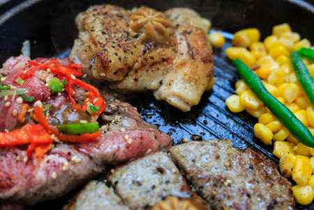 Piece of cooked beef steak with spices and corn served on metal plateの写真素材
