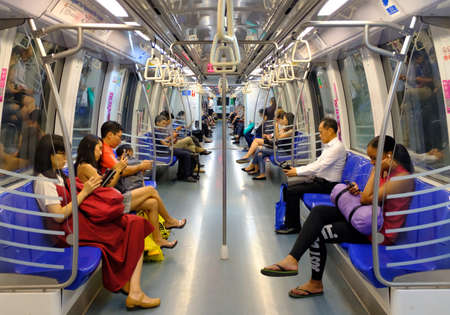 Singapore-21 MAR 2018: Passengers in a crowded Mass Rapid Transit (MRT) subway train in Singapore...