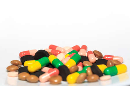 Various pills and capsules on white background