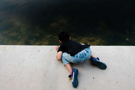 Hunan,Changsha-08 SEP 2019:little boy play water on hard edge river frontの写真素材