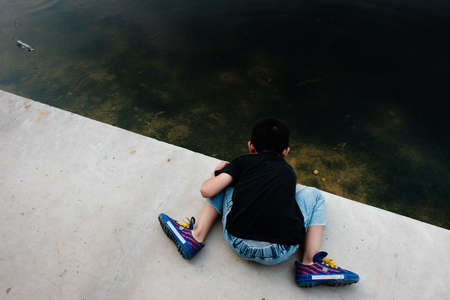 Hunan,Changsha-08 SEP 2019:little boy play water on hard edge river frontの写真素材