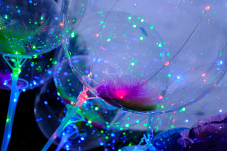 Defocused image of neon lights of illuminated balloons filled with hellium with led diods at nightの写真素材