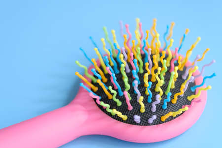 Bright multicolored hair brush on light blue background