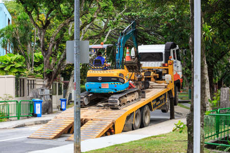 Singapore-08 FEB 2020: small excavator ship by a big truckのeditorial素材