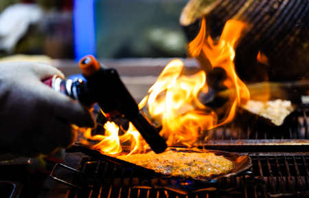 using flame gun to cook meat closeup viewの写真素材
