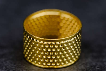 gold color thimble closeup detail view on black backgroundの写真素材