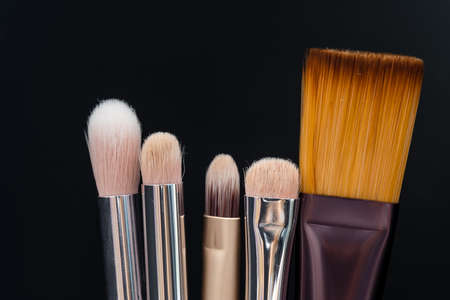 Set of makeup brushes on black background