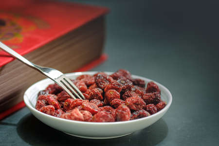 Closeup of a White plate Full of Dried Cranberries and vintage bookの写真素材