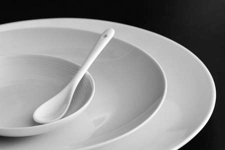 Set of plates with spoon on black tableの写真素材