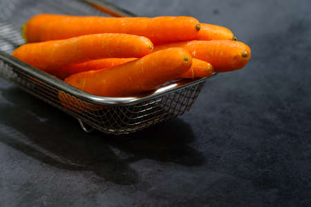 fresh baby carrot in basket isolated on black backgroundの写真素材