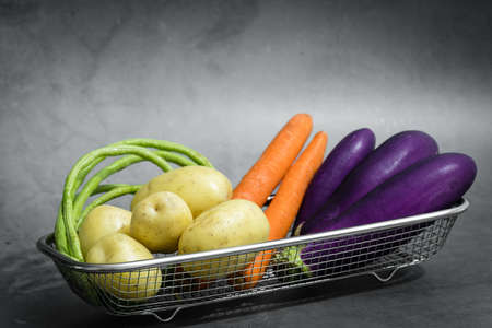 Assorted raw organic vegetables in a metal basketの写真素材
