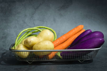Assorted raw organic vegetables in a metal basketの写真素材