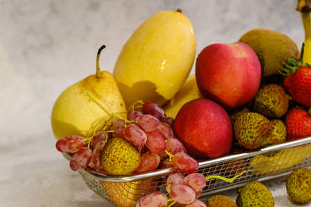 Assortment of exotic fruits in metal basket isolated on whiteの写真素材