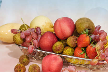 Assortment of exotic fruits in metal basket isolated on light backgroundの写真素材