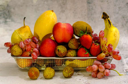 Assortment of exotic fruits in metal basket isolated on whiteの写真素材