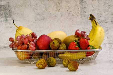 Assortment of exotic fruits in metal basket isolated on whiteの写真素材