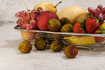 Assortment of exotic fruits in metal basket isolated on whiteの写真素材