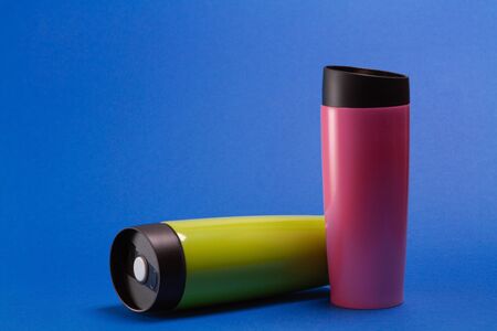 two multi-colored thermal shaker bottles for sports nutrition on a blue background