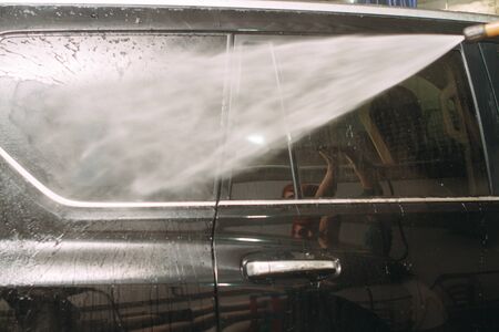 An employee of the car wash thoroughly washes conducts detaling and applies protective equipment to the body of an expensive carの写真素材