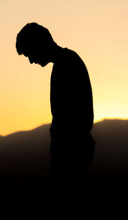 Silhouette of a man praying on the street in a beautiful landscapeの写真素材